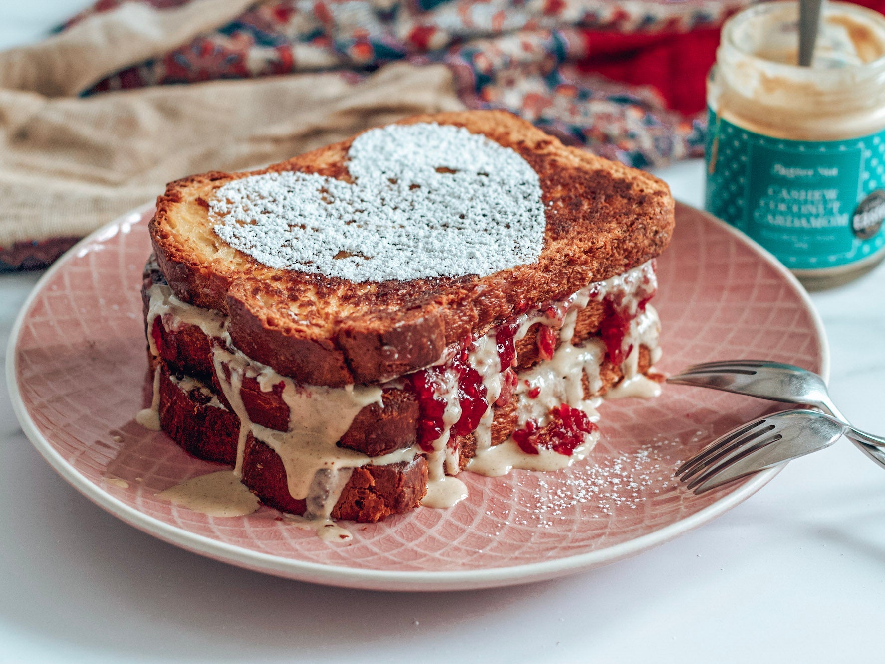 Stack of french toast with Butter Nut of London Cashew Coconut Cardamom nut butter and Raspberry Jam bursting out.
